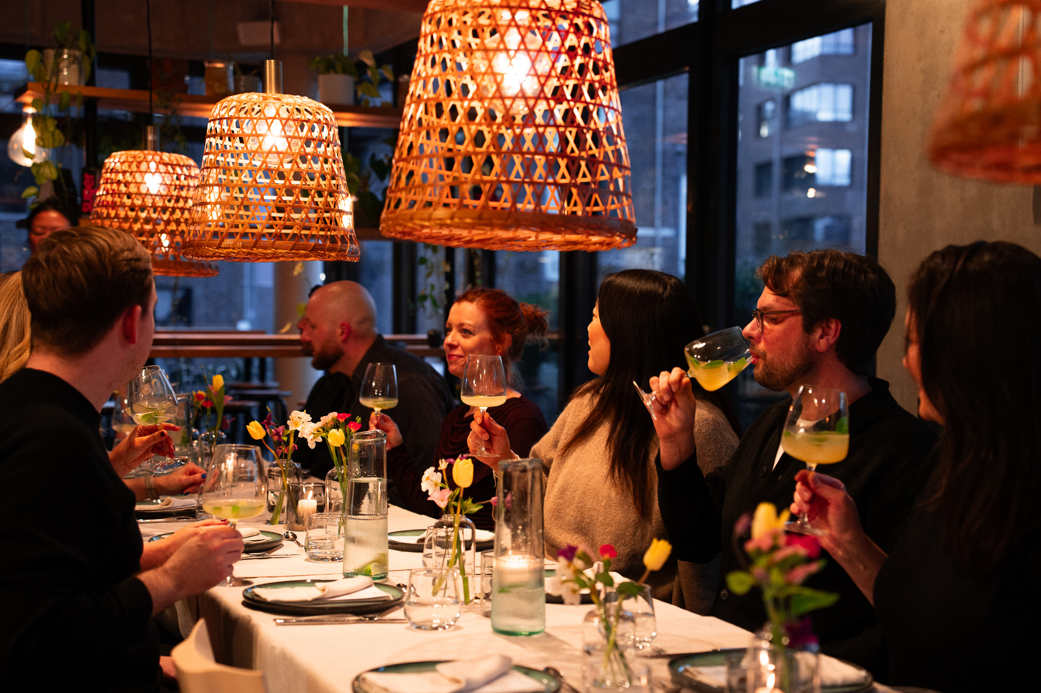 Gäste stoßen an der Tafel unter Bambusleuchten an