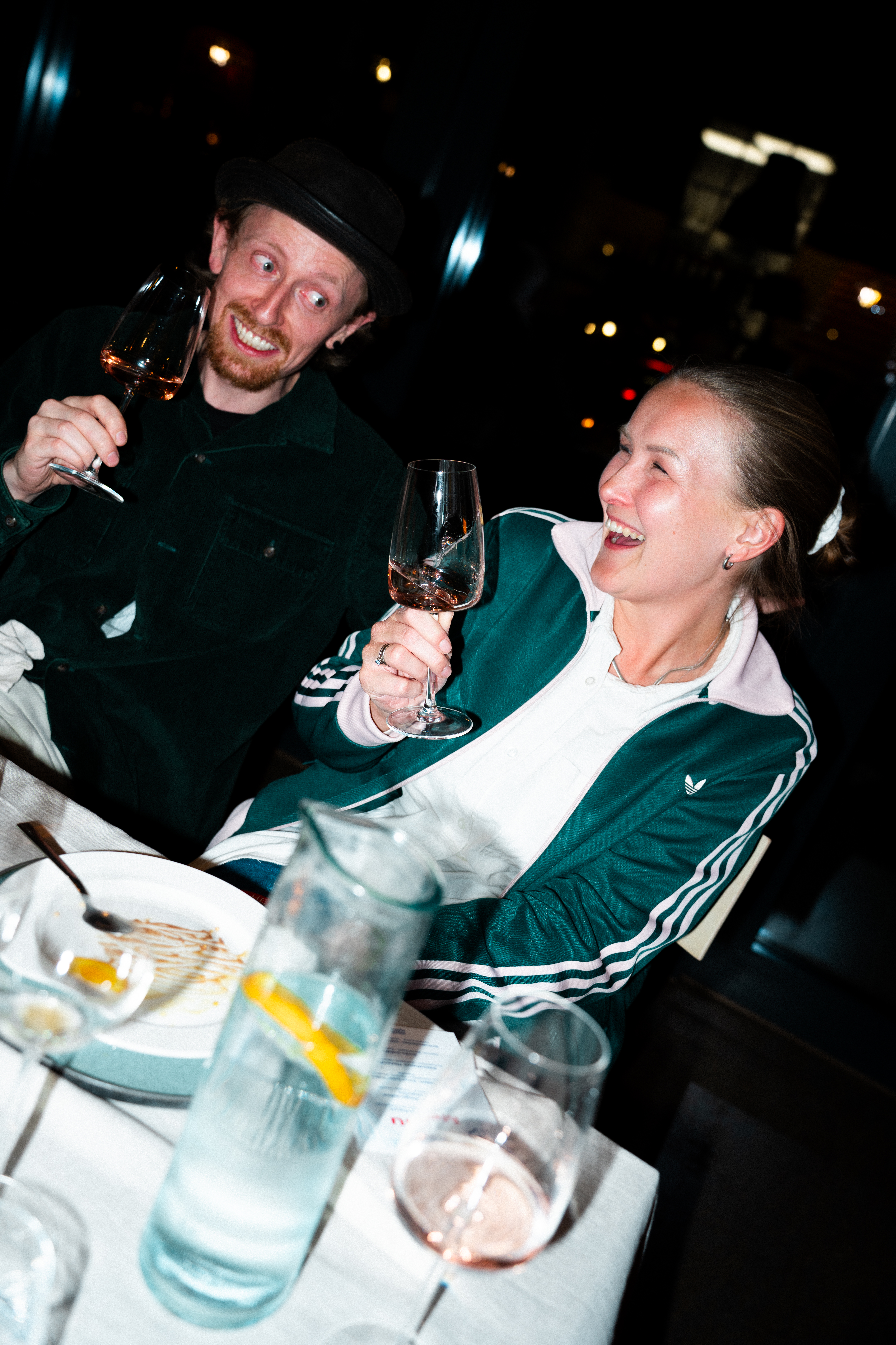 Zwei Gäste stoßen an der Tafel mit Wein an