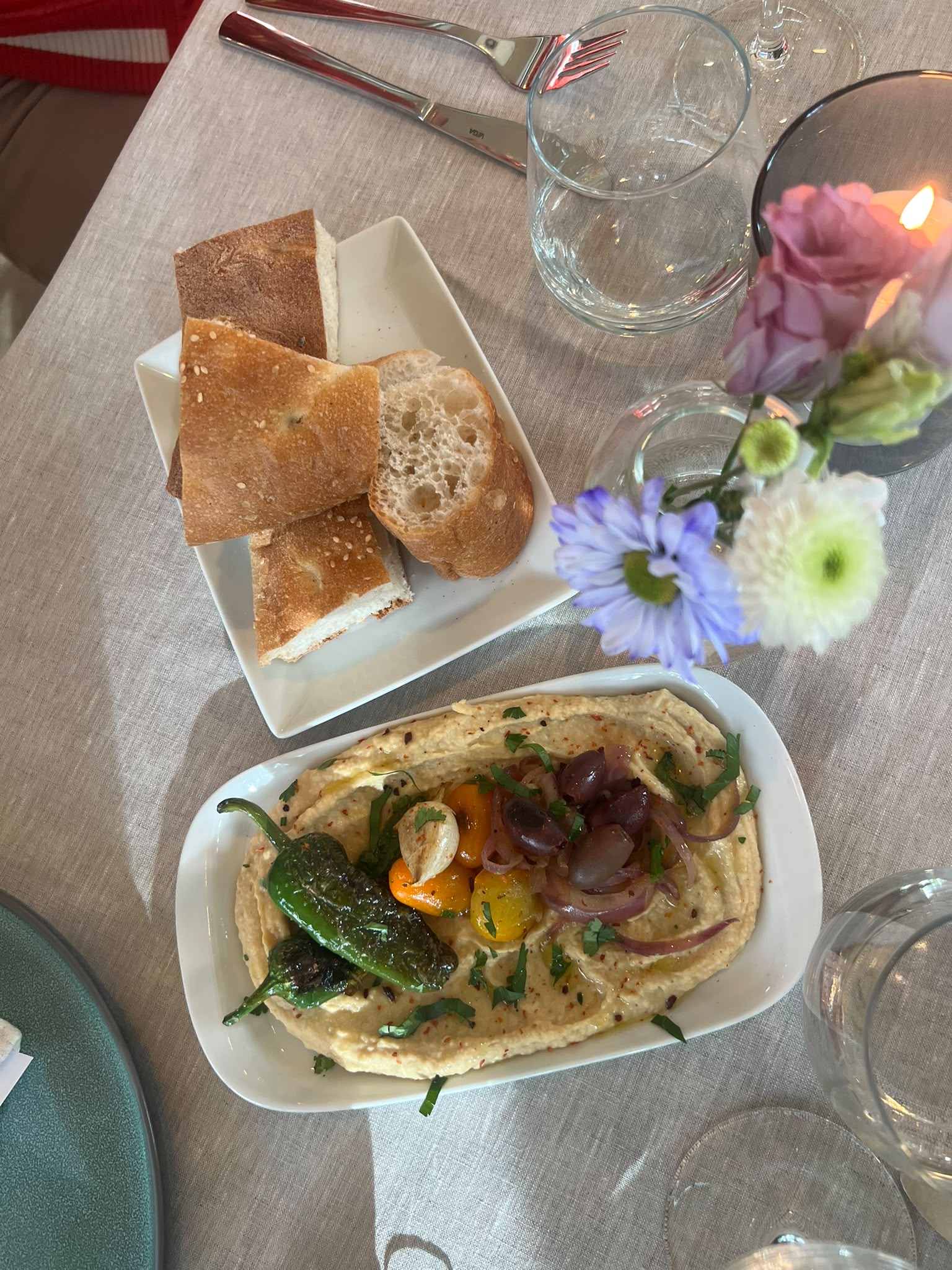 Hummus mit gerösteter Paprika, Oliven und Brot auf der Tafel